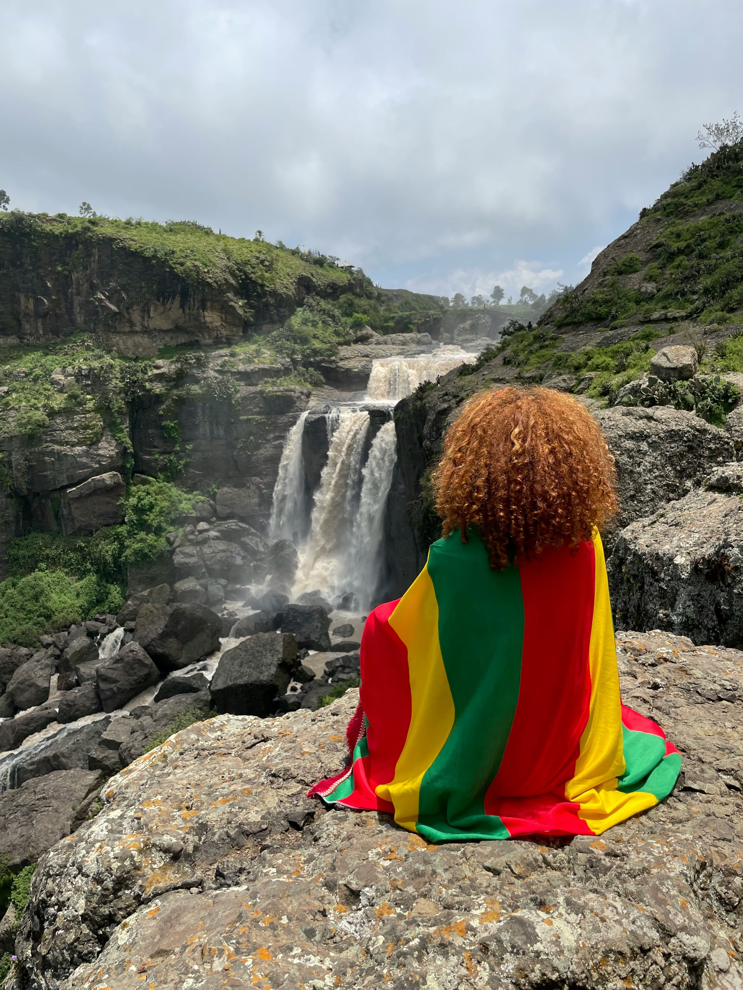 Person sitting by waterfall in Simien Mountains